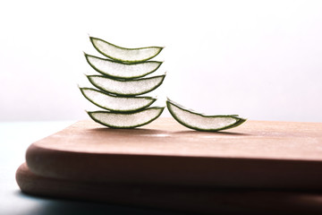 aloe vera slices stacked on bamboo cutting surface, isolated on white background