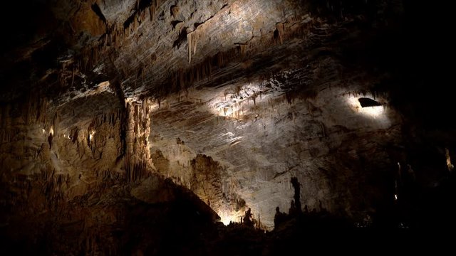Beautiful giant cave with mysterious light. Stalactites and stalagmites illuminated by beautiful changing light. Giant grotto underground. Underground Kingdom. Journey to the center of the earth.