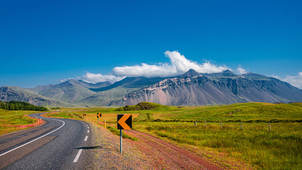 Isländische bunte und wilde Landschaft und asphaltierte Straße zur Sommerzeit und blauer Himmel, Island, Panorama