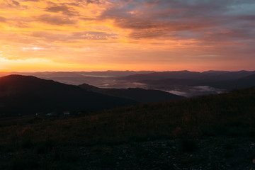 Bright red sunset over the mountains, fog over the terrain