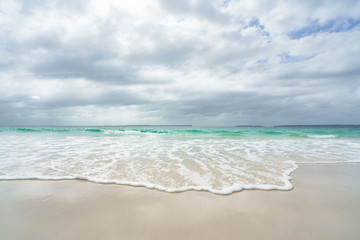 Fototapeta na wymiar Smooth wave rolling onto a white sand beach