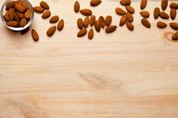 Almonds in glass transparent bowl on wooden background. Almond concept with copy space