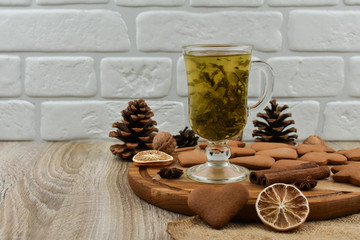 Zero waste concept. New Year. Glass cup of green tea with cookies on a wooden tray. Ginger, star anise, cones, lemon.