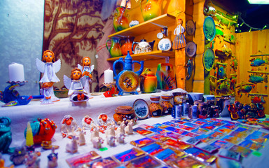 Christmas Ceramics Decorations on Christmas Market at Riga, Latvia. Advent Fair, and Stalls with Crafts Items in Bazaar. Night street Xmas and holiday fair in European city or town, December. - obrazy, fototapety, plakaty