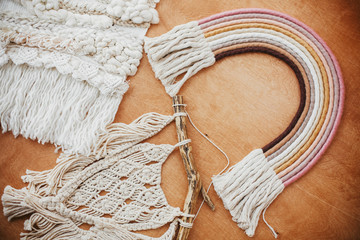 Stylish macrame and rainbow decoration on wooden table. Modern boho wall hanging and rope rainbow...