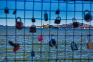 Alcatraz through a fence covered in locks 