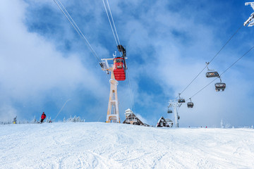 Seilbahn, Schwebebahn vor blaumem Himmel mit vereistem Mast, neben Sessellift, mit Bergh&uuml;tte im Hintergrund