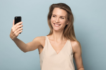 Fototapeta premium Smiling attractive woman taking selfie, using mobile phone