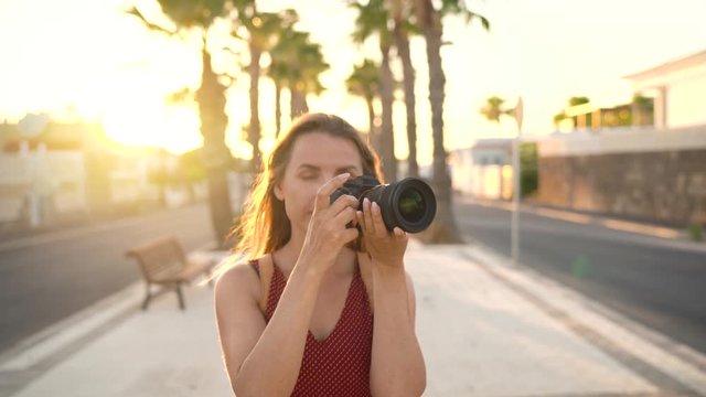 Photographer tourist woman taking photos with camera in a beautiful tropical landscape at sunset