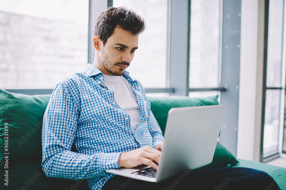 Poster serious male software developer working remotely on modern laptop device watching tutorial webinar o