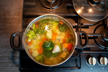 Homemade chicken vegetable soup, overhead, close-up view on a white background. bowl of fresh homemade soup to cure flu at table, top view. Vegetable soup with ingredients carrot cauliflower potato 