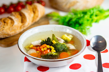 Homemade chicken vegetable soup, overhead, close-up view on a white background. bowl of fresh homemade soup to cure flu at table, top view. Vegetable soup with ingredients carrot cauliflower potato 
