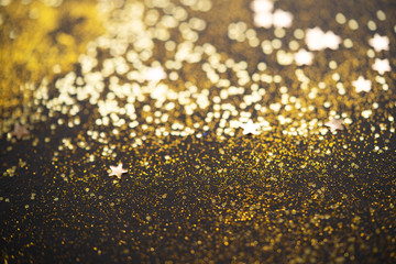 Beautiful Christmas light background. Abstract glitter bokeh and scattered sparkles in gold, on...