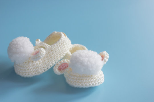 Close-up, knitted shoes for newborn on blue background