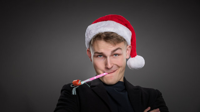 A handsome executive enjoys an office christmas party wearing a red hat & has a blow tickler in his mouth