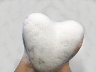 Heart made of foam on a white background. Big heart in the hands. Snow heart. 
