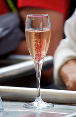 A glass of pink fizzy tasting drink stands on the counter at a fair in a small town in France