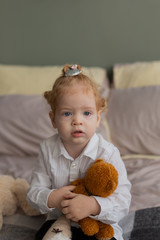 Beautiful little girl on the bed plays with plush toys.