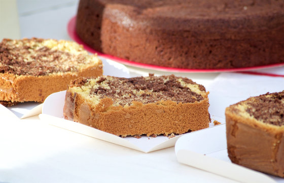 eces of chocolate cake for tasting lie on the counter against the background of a large cake at a market in a small town in the South of France