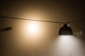 Hanging street lamp at night in dense fog