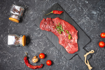 Raw fresh marbled meat Steak and seasonings on dark stone background