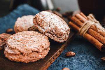 Homemade bakery, chocolate cookies with powdered sugar, cinnamon sticks, on blue napkin
