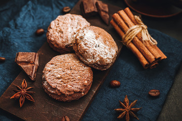 Homemade bakery, chocolate cookies with powdered sugar, cinnamon sticks, star anise on blue napkin