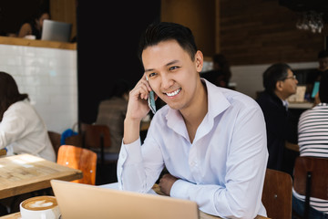 Joyful freelancer sitting in cafe and smiling