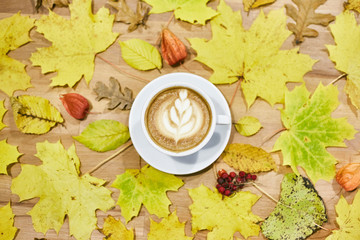 Autumn flat lay composition with dry leaves wreath frame and coffee latte cup on wooden background. 
