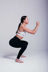 girl shows poses for yoga and warm-up in black leggings and a white T-shirt barefoot on a white...