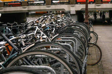 Bicycles parked in line with an Amsterdam canal next to it and the train passing in the background over a bridge