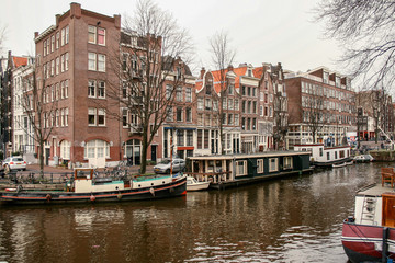 Fototapeta na wymiar Amsterdad Canal, with boats and houses on both sides of the river and houses around