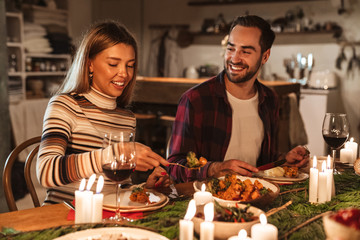 Photo of caucasian joyful couple eating while having Christmas dinner