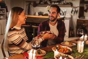 Photo of caucasian joyful couple eating while having Christmas dinner
