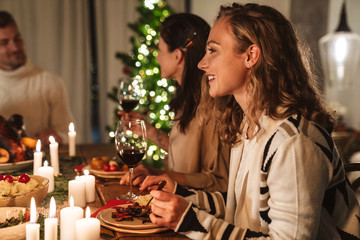 Photo of beautiful joyful people eating while having Christmas dinner