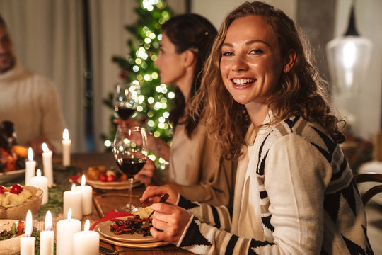 Photo of beautiful cheerful people eating while having Christmas dinner