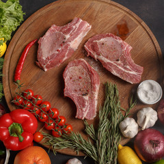 Raw pork steak on a wooden board. composition of various cooking products. Top view.