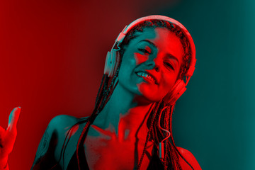 Dj woman with tree braid hair and dancing with headphones.