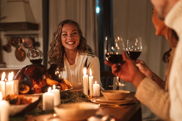 Photo of people drinking wine and smiling while having Christmas dinner