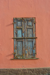 Old boarded up windows on a pink wall.