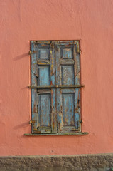 Old boarded up windows on a pink wall.