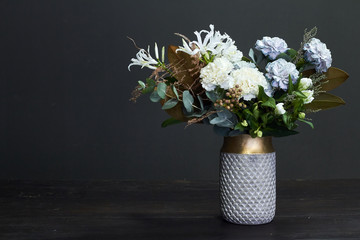 White toned bouquet in vintage style in a ceramic vase on a dark background, selective focus