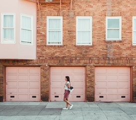 girl walking through the city next to a pink building