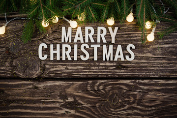 Merry Christmas. Christmas composition with fir branches and lights on a wooden background. Christmas background.