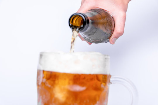 A Female Hand Holding A Bottled Beer And Pouring Into The Glass. White Background