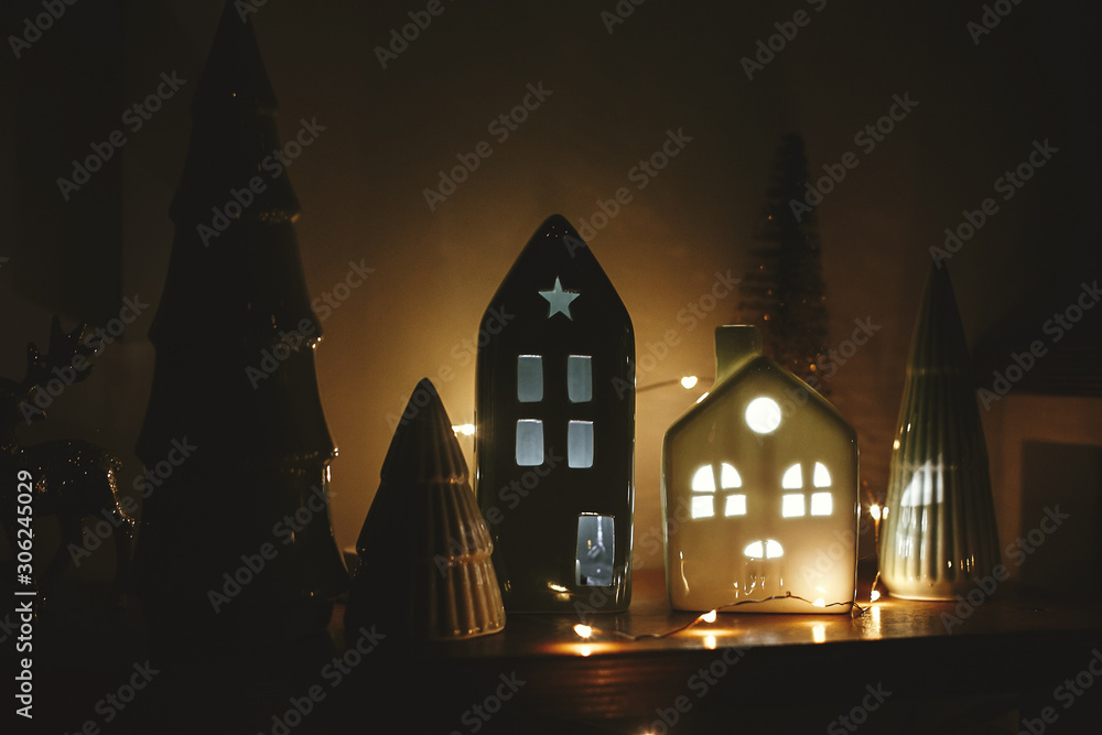 Wall mural Christmas little houses with lights and christmas trees in night. Miniature houses among trees in christmas evening. Stylish festive decorations. Winter wonderland