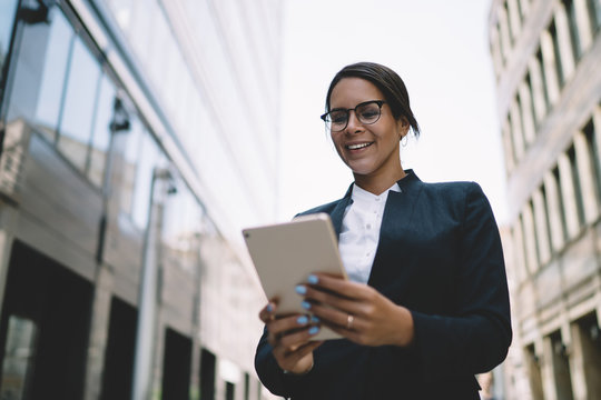 Positive Female Trader Enjoying Break Time For Communication With Friends In Social Network Using 4g Wireless On Touch Pad, Happy Businesswoman In Stylish Eyewear Reading News In Company Chat