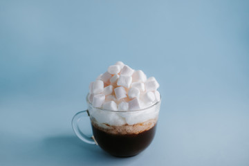 cup of coffee with whipped cream and marshmallows on a blue background
