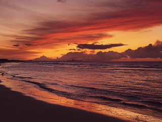 Colorful sunset at the beach with industrial complex in the distance