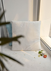 Two pillows white and light blue on the window sill in daily light. Mock up for textile fabric design. print and more.